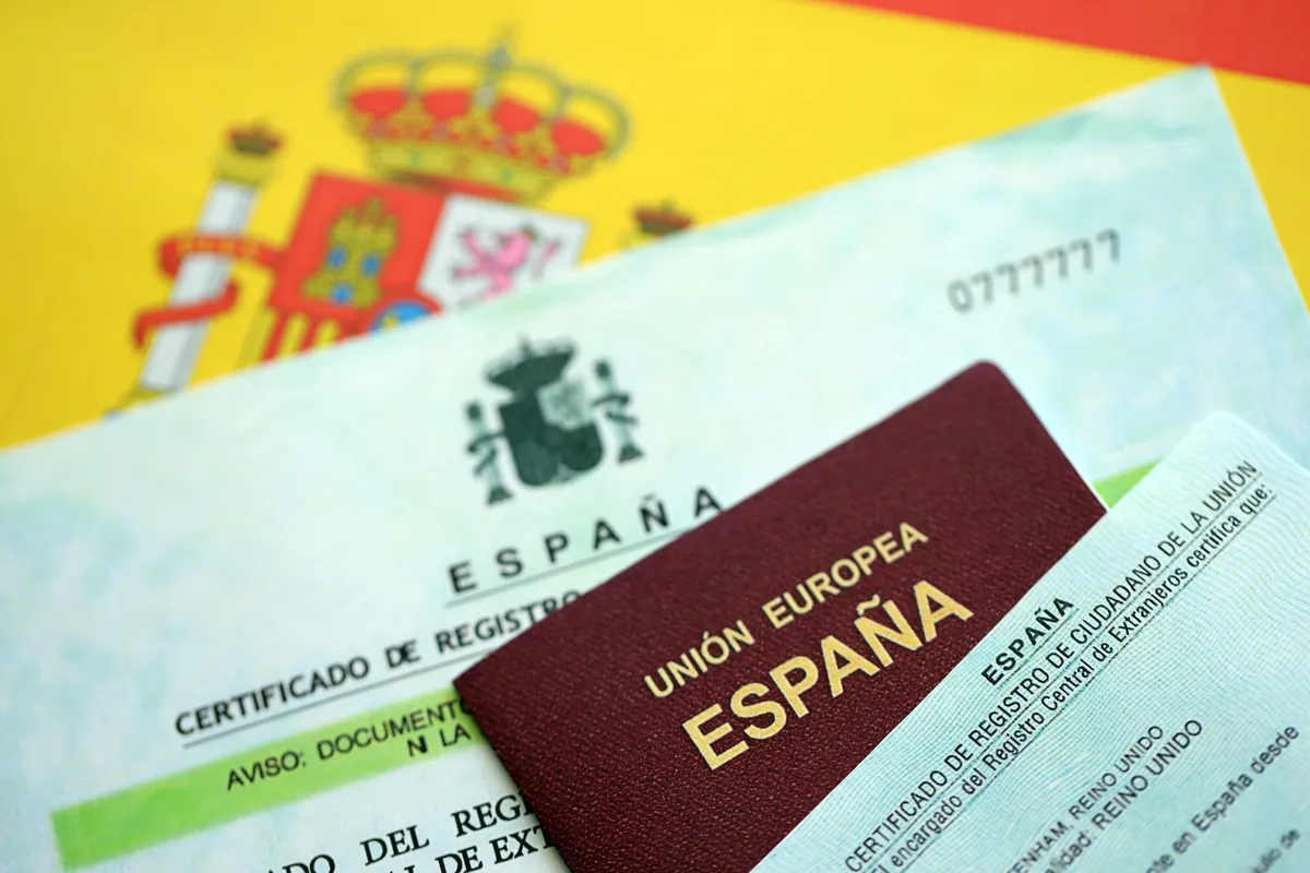Pasaporte español sobre documentos de registro y una bandera de España