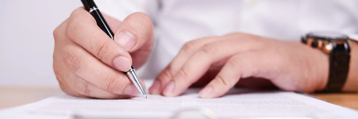 Manos de una persona firmando un documento