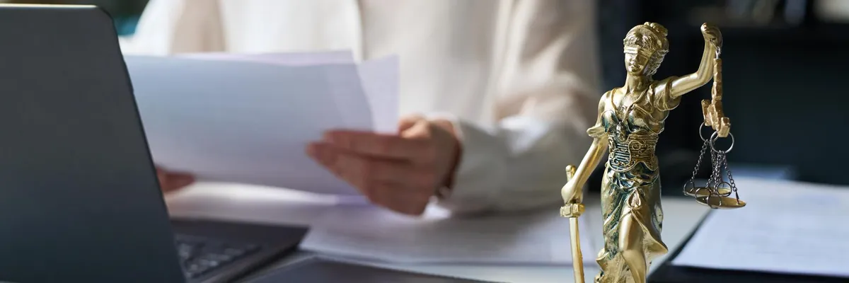 Revisión de documentos junto a un ordenador y una figura de la Justicia